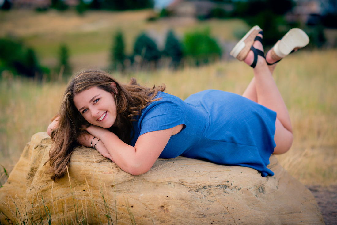 Girl in blue dress smiling at camera for senior pictures